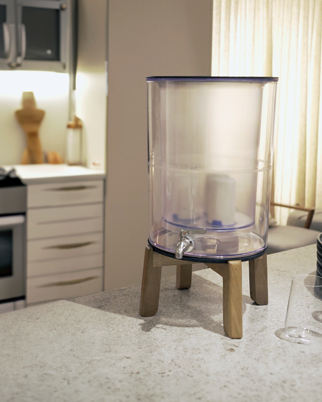 Purificador Acqualive transparente em cozinha moderna com luz dourada, água ideal para café especial